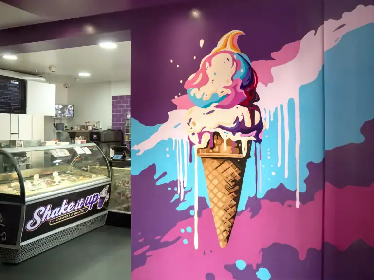 Vibrant ice cream cone mural with colorful swirls and drips on purple wall.